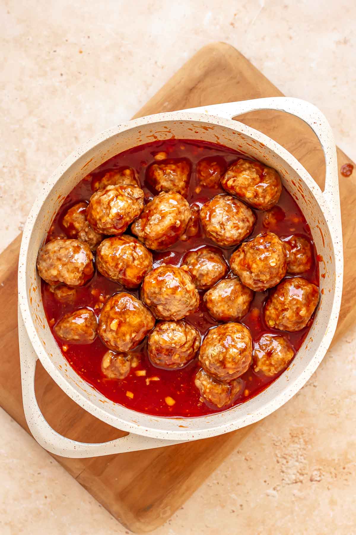 Cooked meatballs in honey sriracha sauce in a saucepan.
