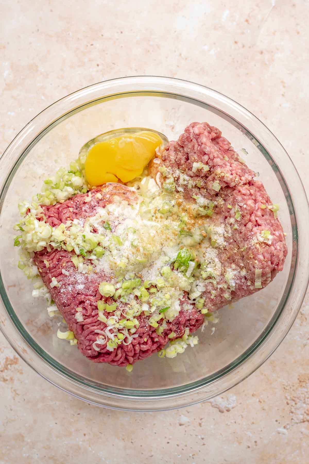 Ground meats and meatball ingredients in a bowl before mixing.