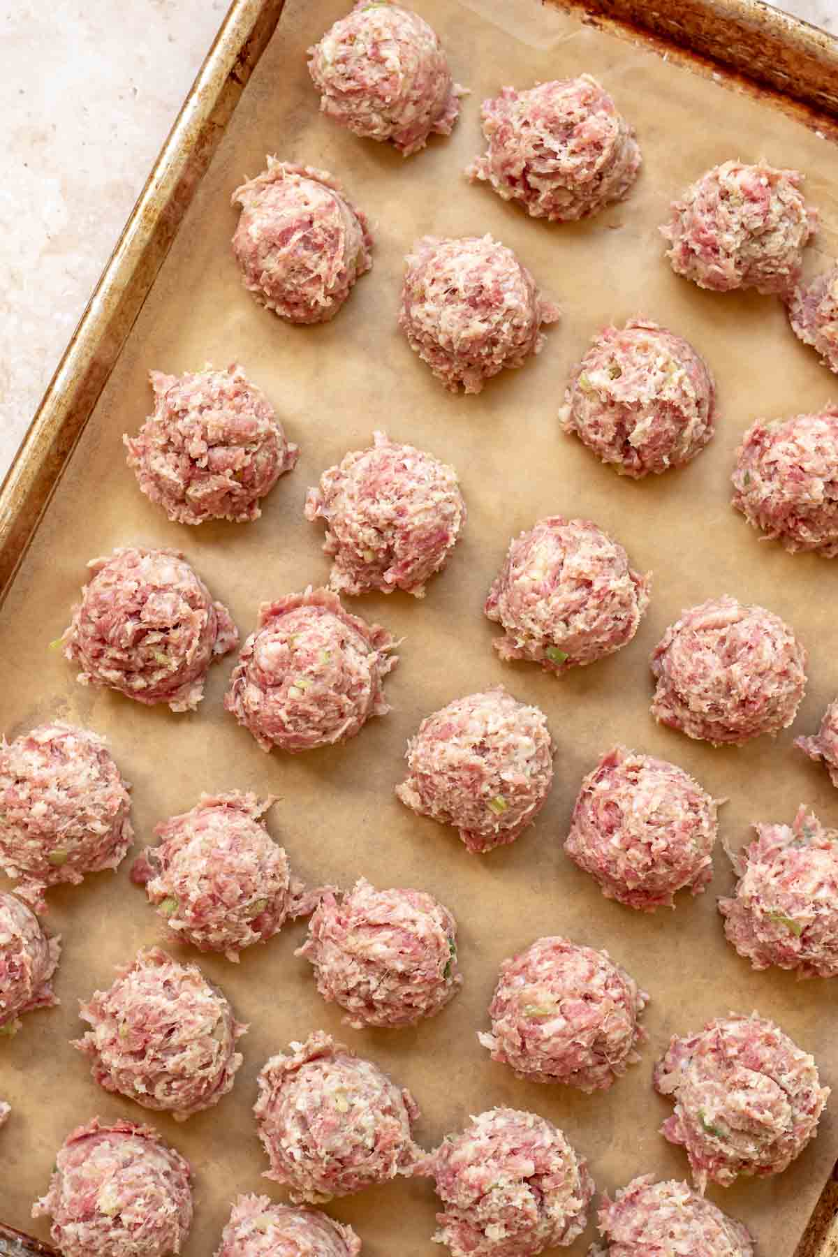 Scoops of meatballs on a prepared pan.