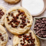Chocolate chip sugar cookie on a platter with sugar and mini chocolate chips next to it.