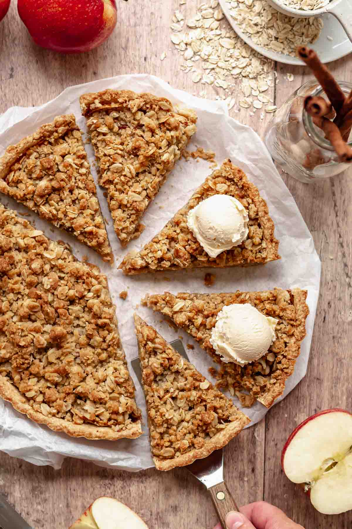 Sliced apple crumble tart with a scoop of ice cream on two of the slices.