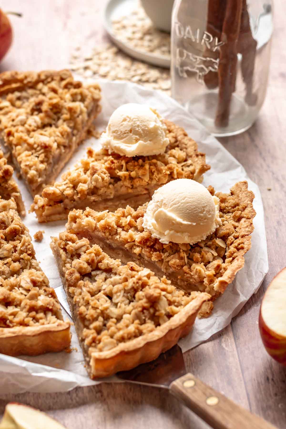 Sliced apple crumble tart with a scoop of ice cream on two of the slices.
