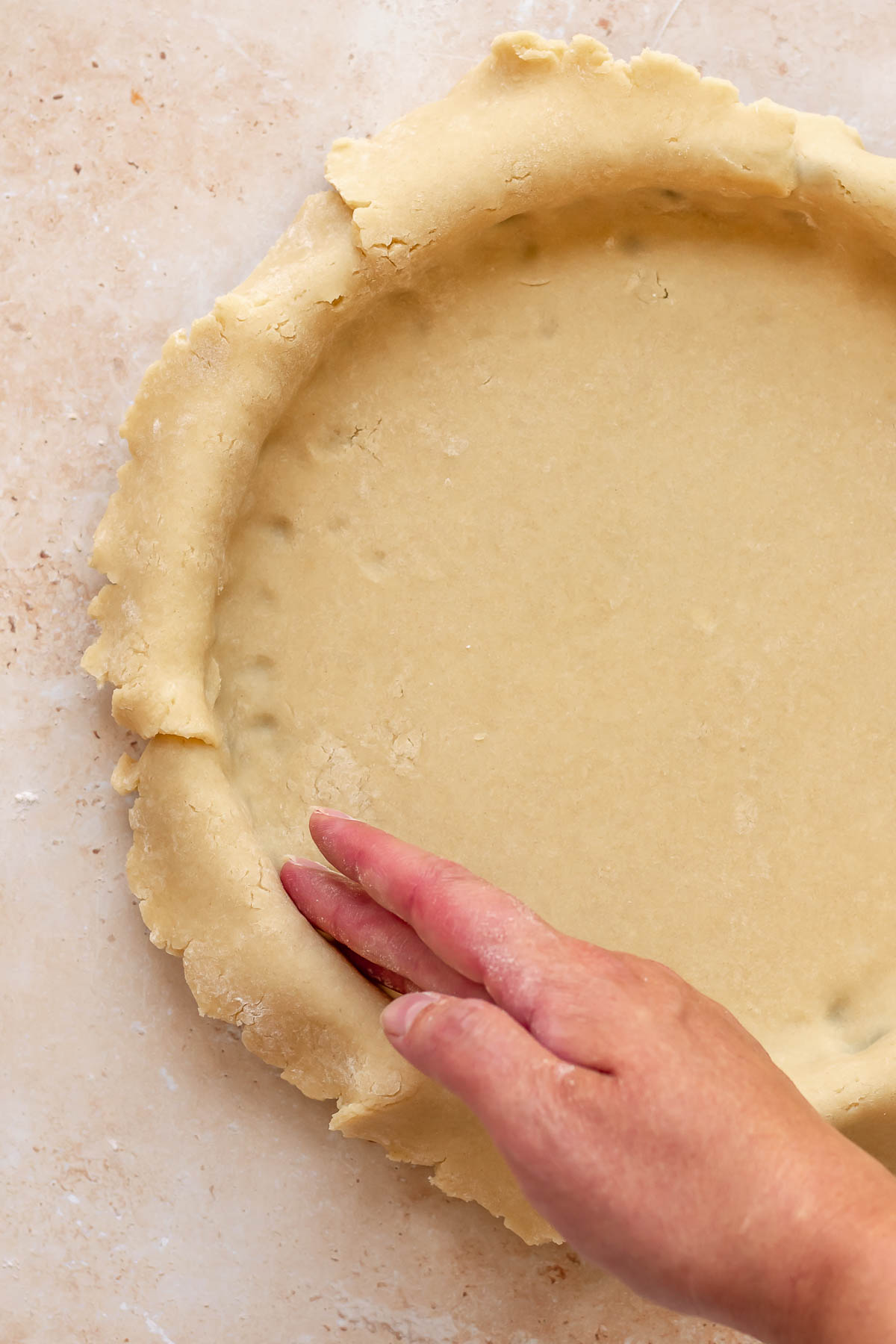 A hand presses tart dough into a tart pan.