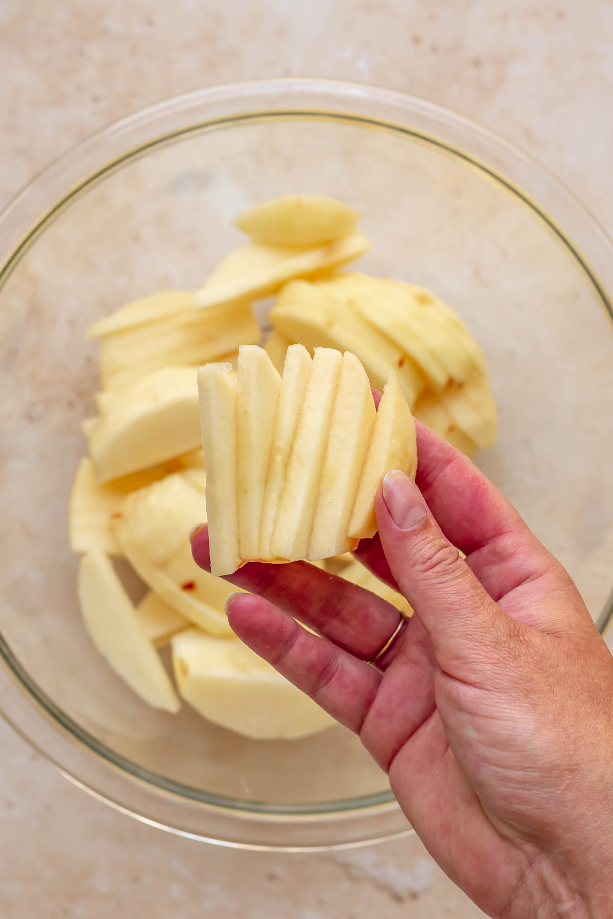 A hand holds a fan of sliced apples.