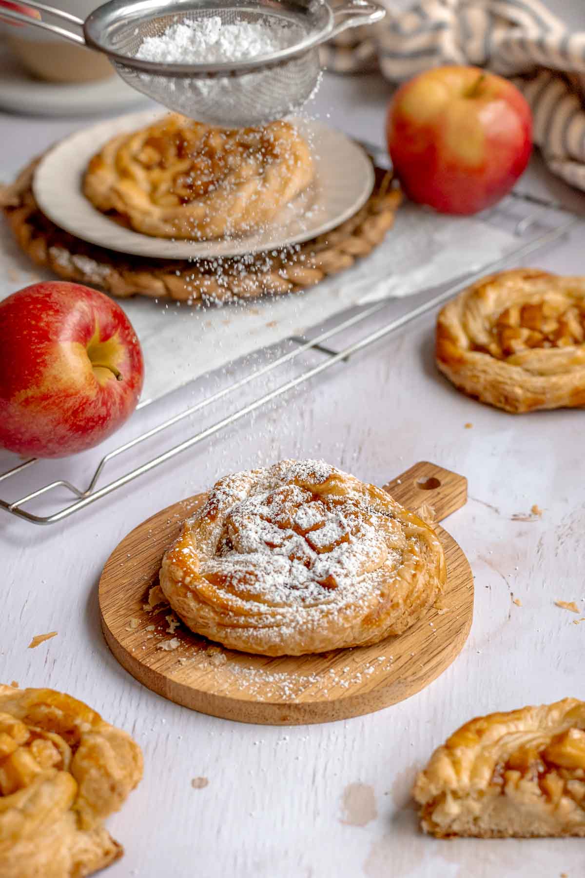 Powdered sugar being dusted on top of an apple danish.