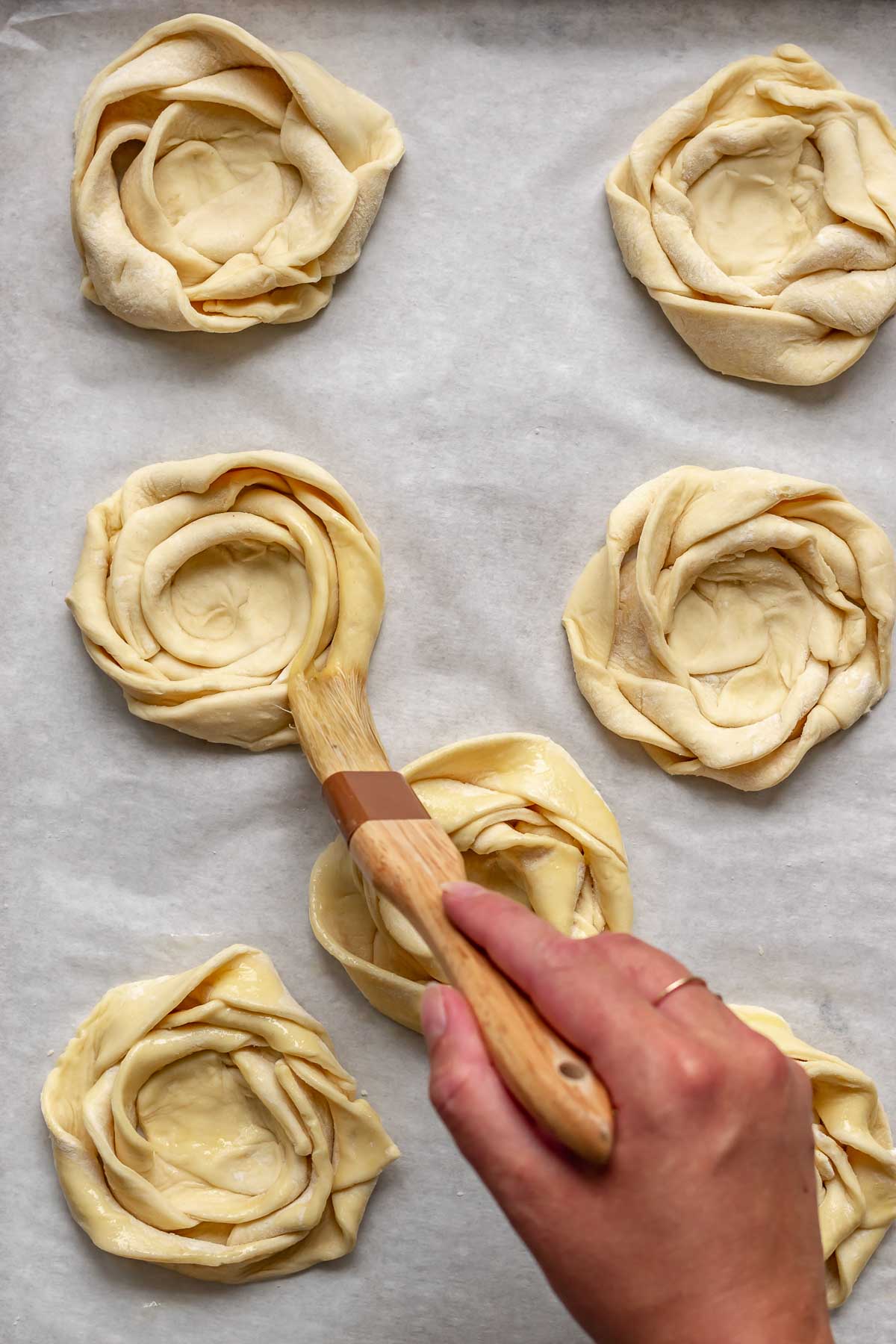 A pastry brush adds egg wash to the puff pastry roses.