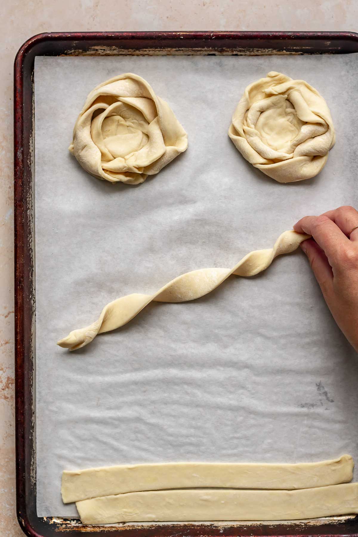 A hand holds a corkscrewed piece of puff pastry.