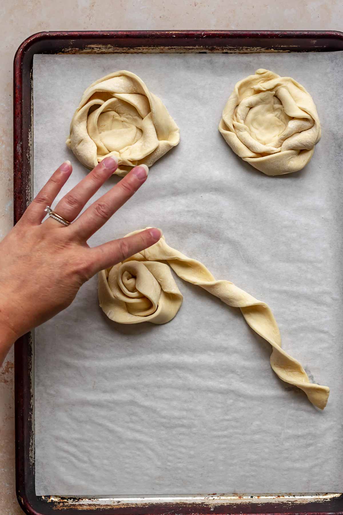 A hand presses together two strips of coiled puff pastry.