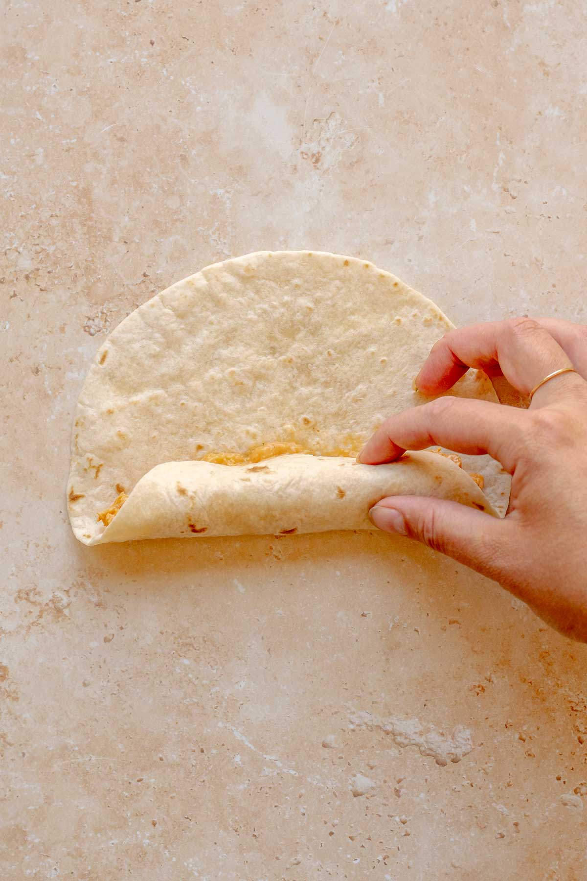 A hand rolls up a tortilla like a cigarette.