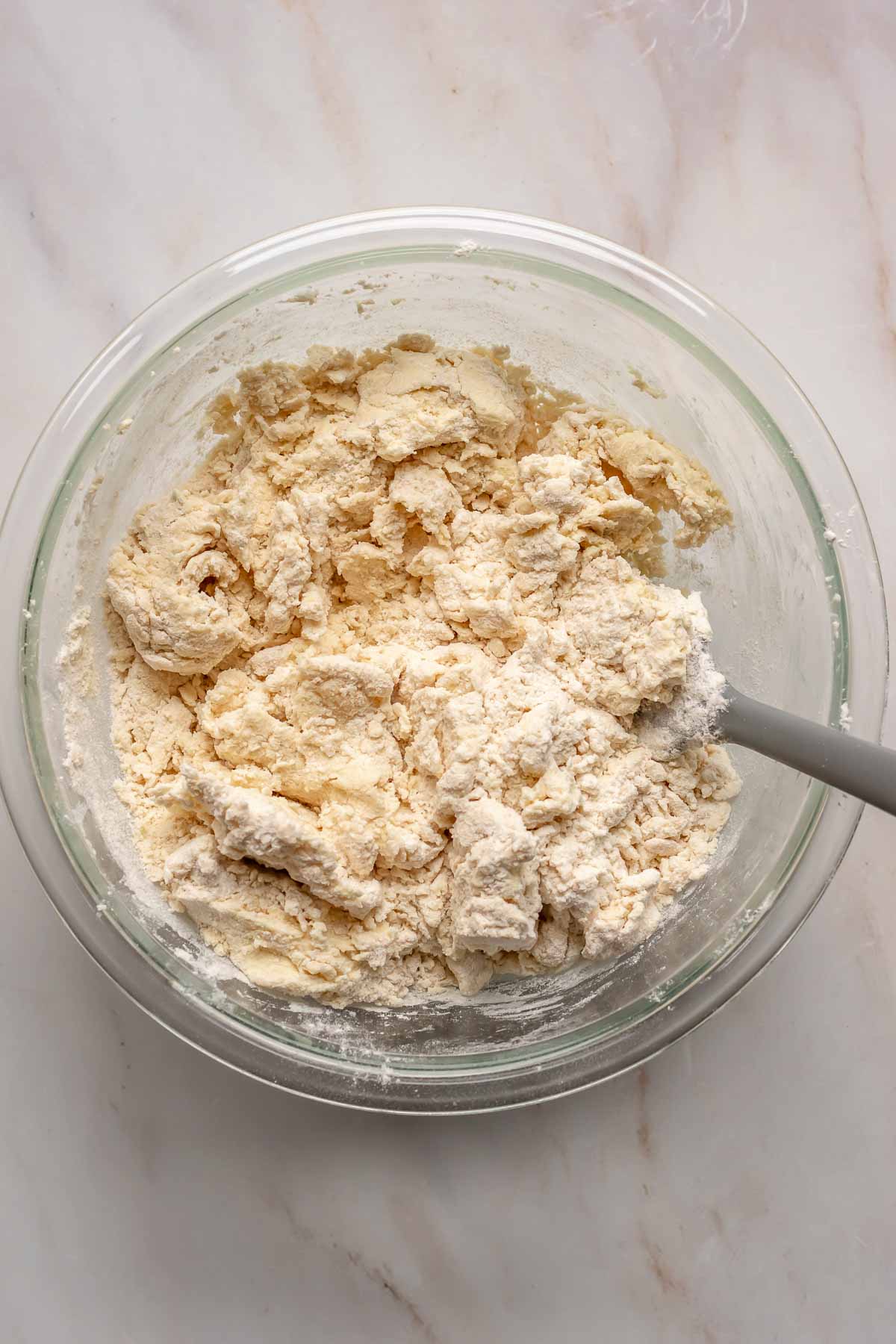 A rubber spatula mixes flour into the sugar cookie dough.