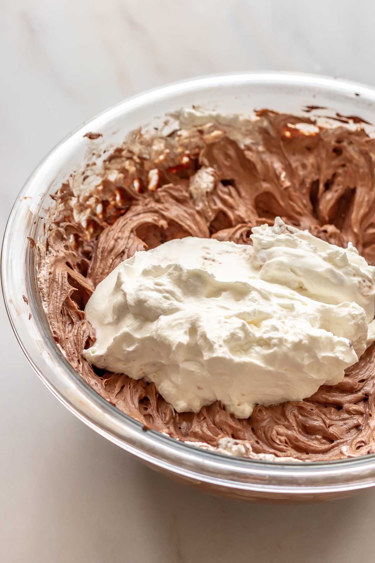 Whipped cream on top of chocolate cheesecake batter.