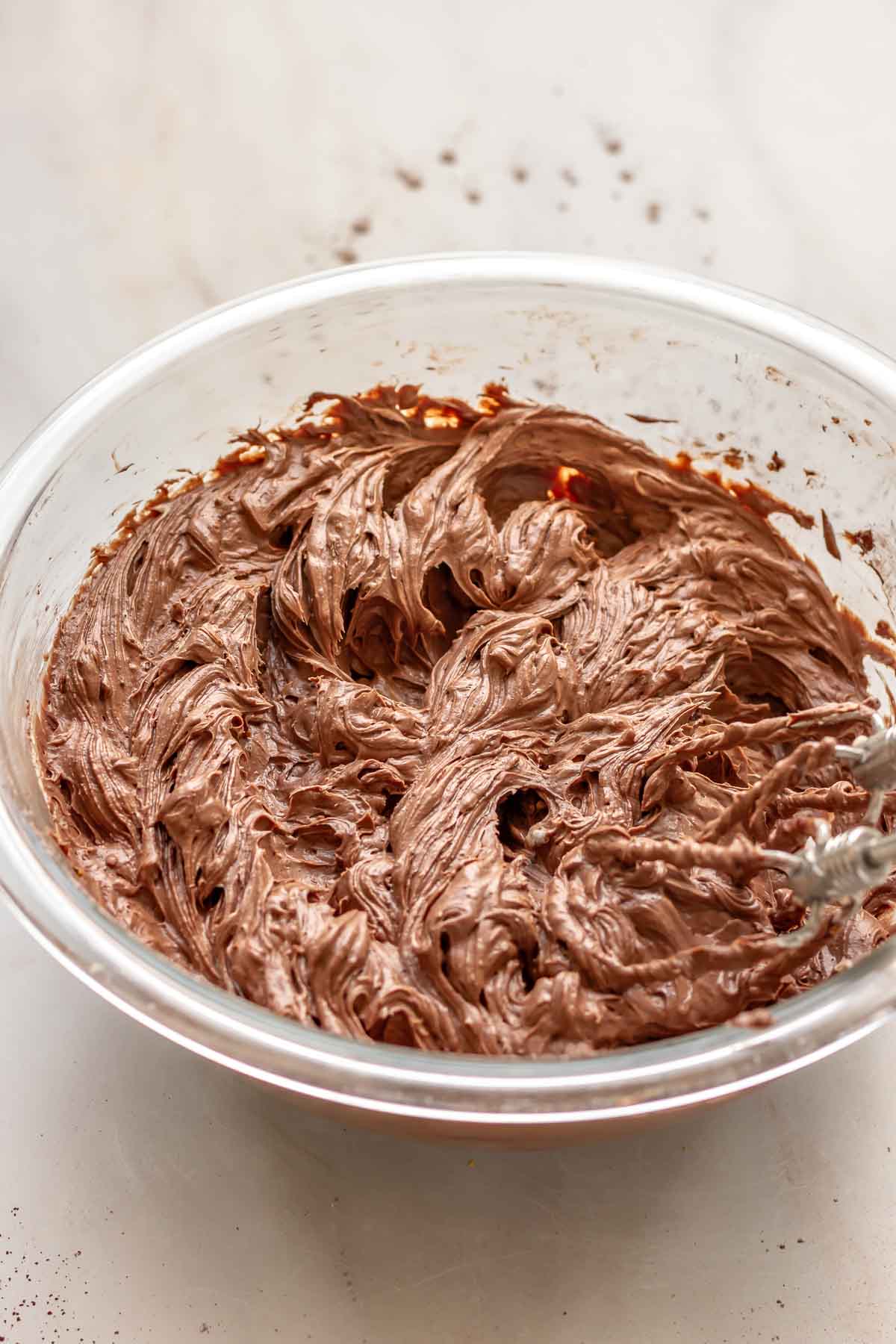 A hand mixer beats together chocolate cheesecake filling.