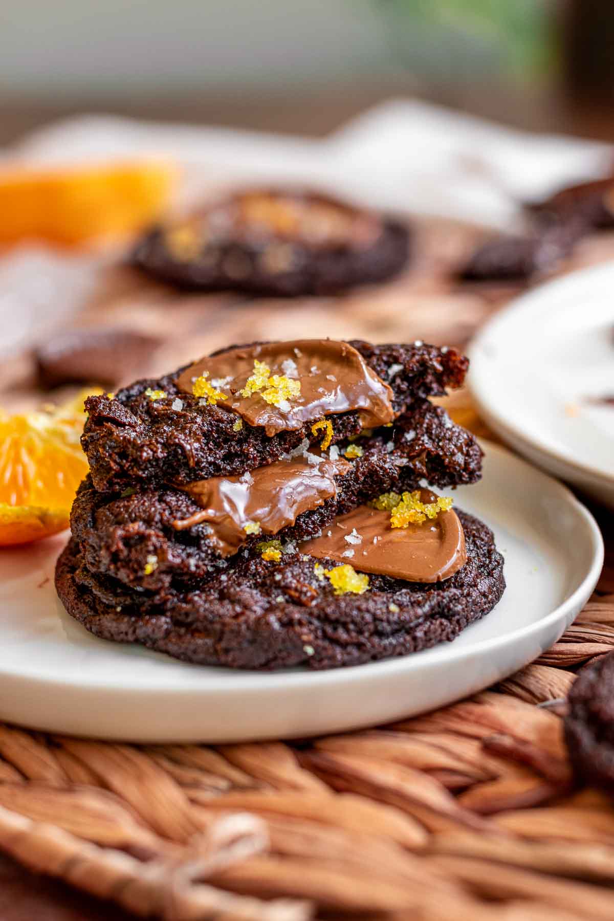 Chocolate orange cookies stacked on a plate. The top two are broken in half.