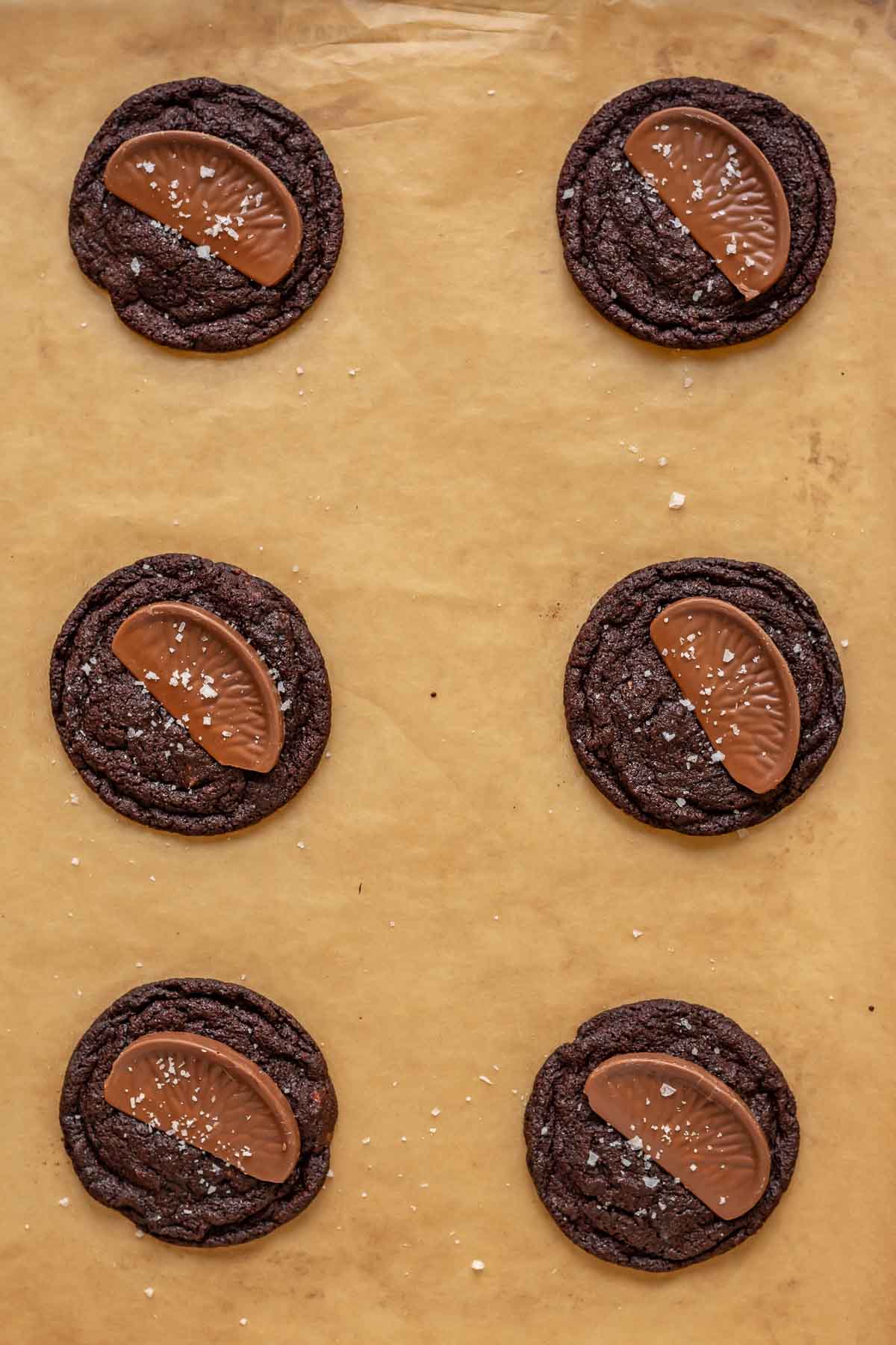 Baked chocolate cookies with slices of chocolate orange on top of each.