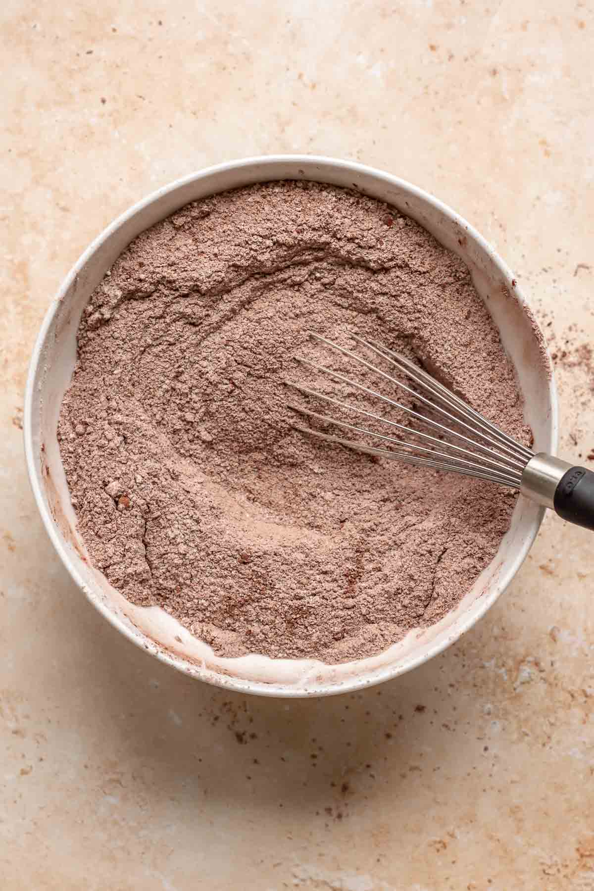 Dry chocolate cake ingredients whisked together in a bowl.