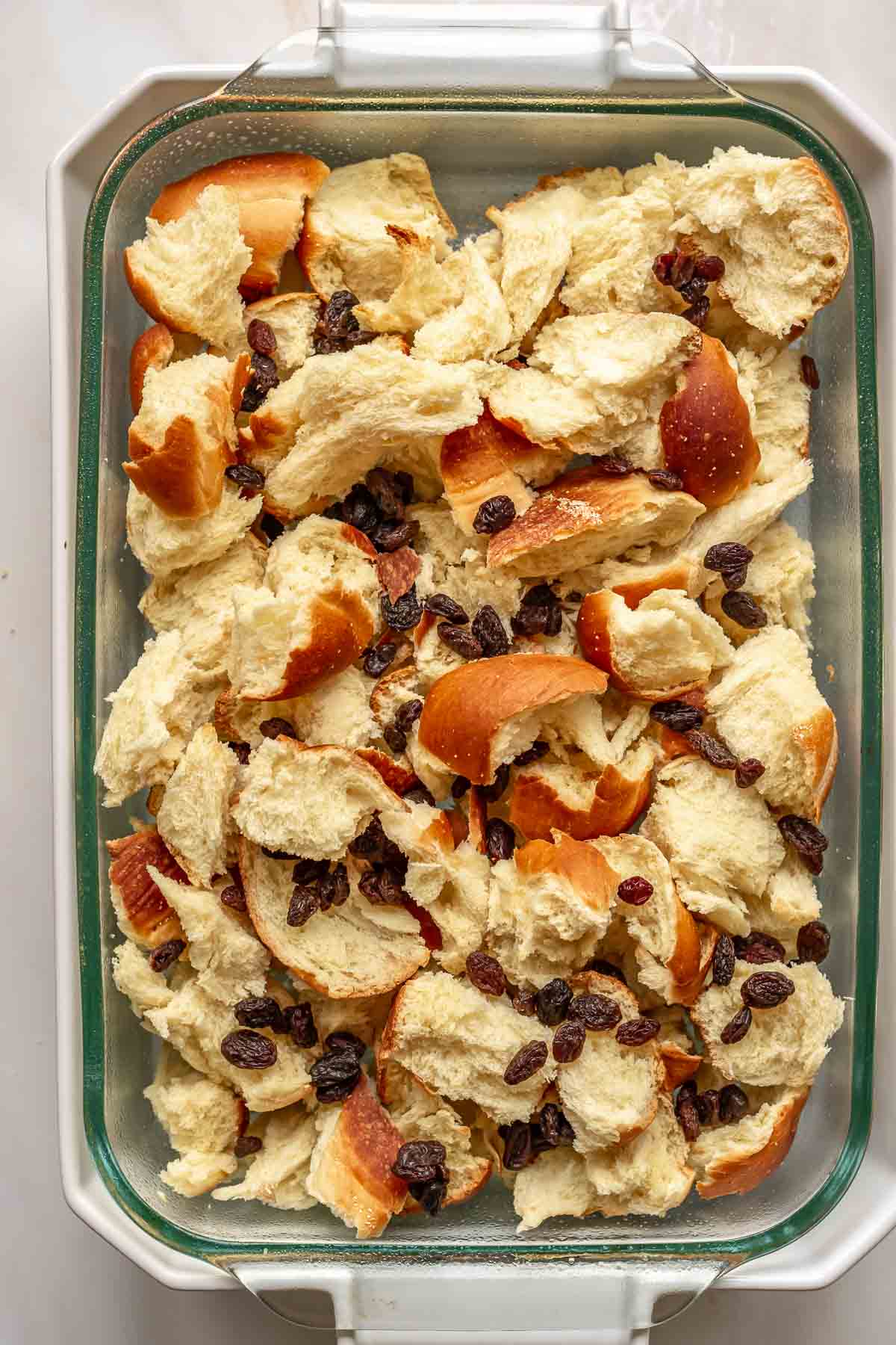 Raising and challah bread pieces in a casserole dish.