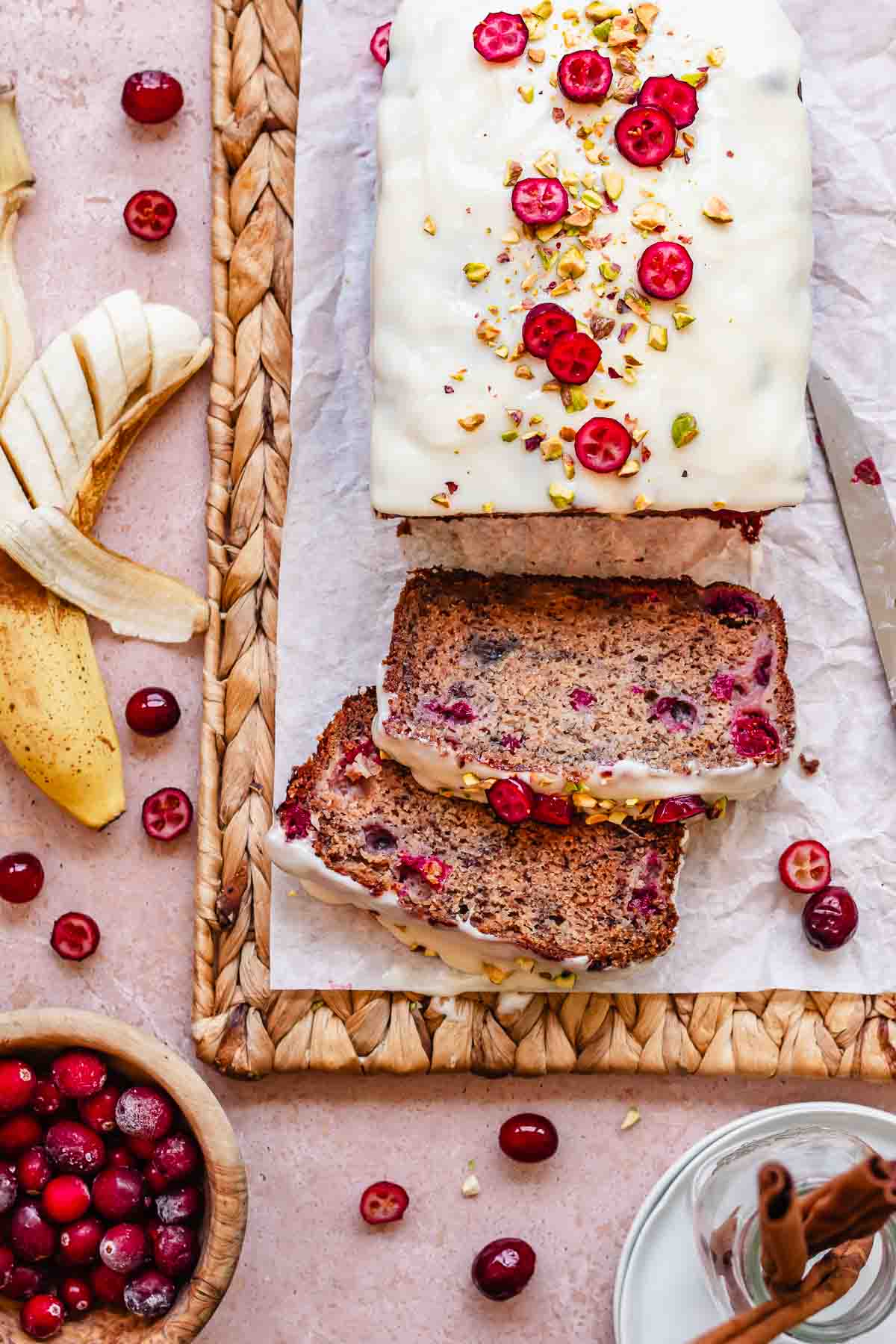 Sliced cranberry banana bread with glaze and pistachios.