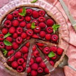 Sliced chocolate raspberry tart on a platter.