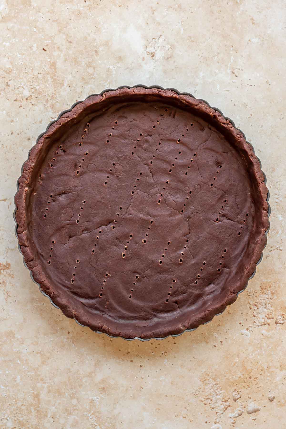 Chocolate sweet tart crust in a tart pan before baking.