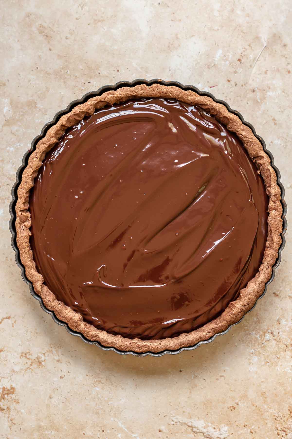 Dark chocolate ganache in a tart shell spread smoothly.