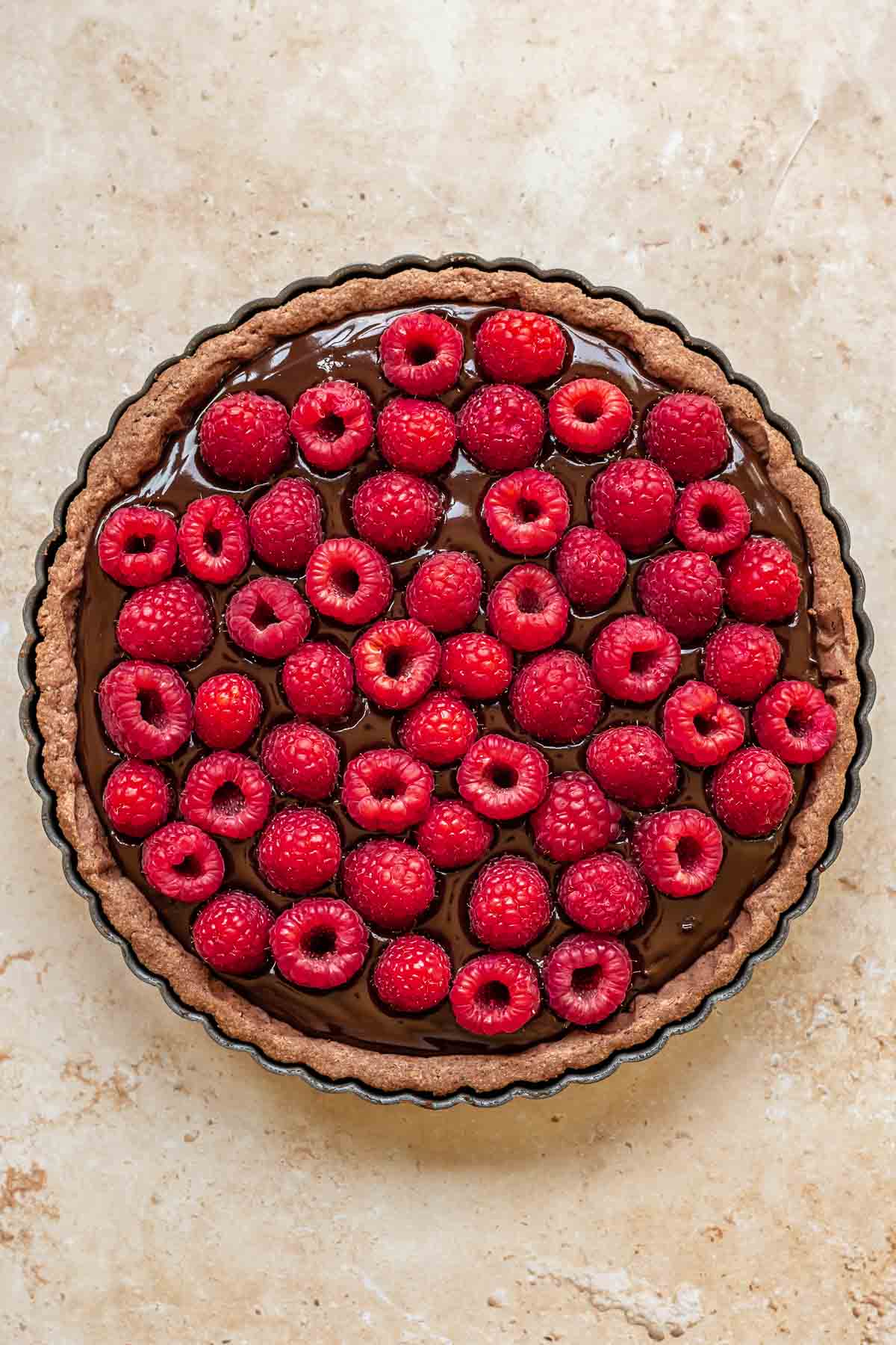 Raspberries pressed into chocolate ganache in a tart.