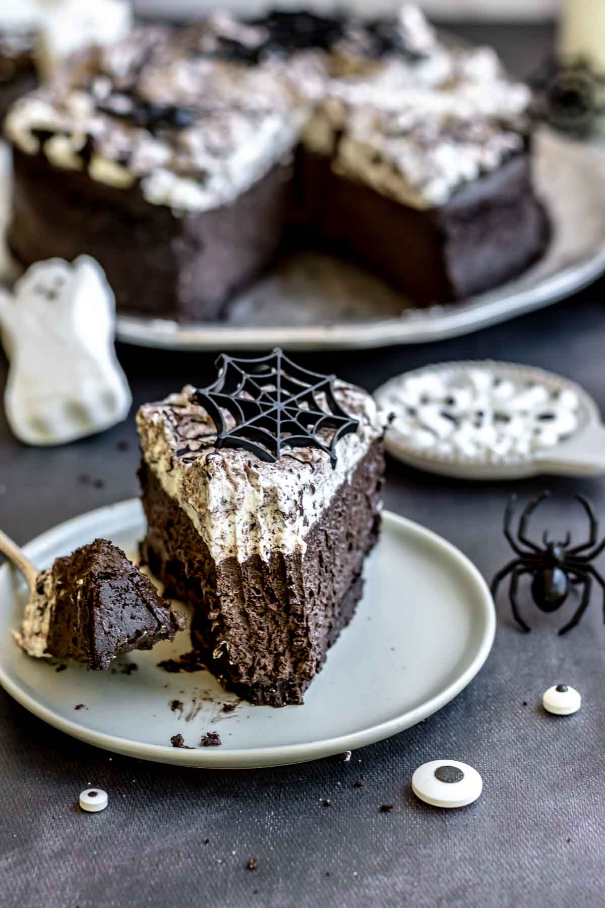 A slice of halloween cheesecake on a plate with a fork having a bite removed.
