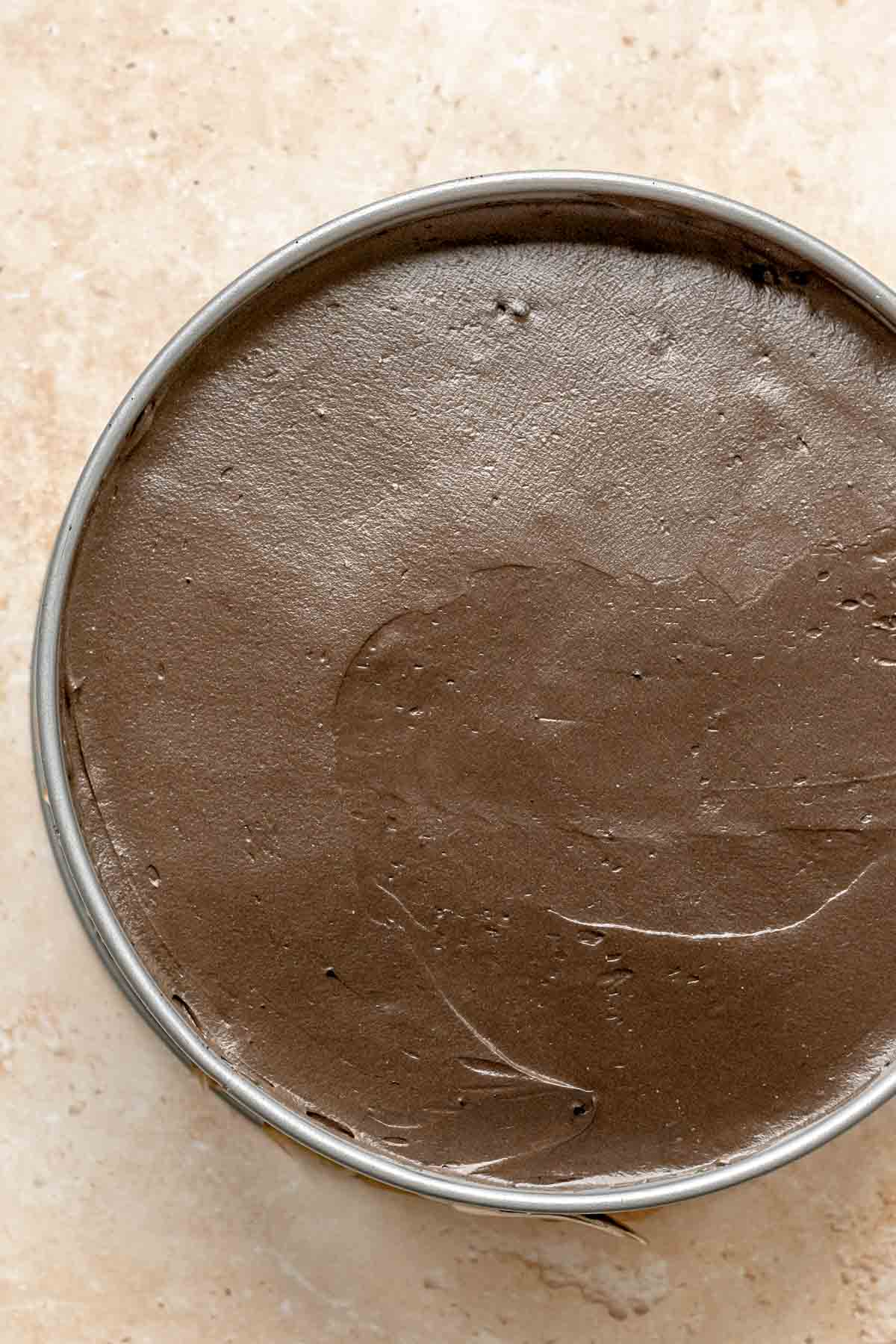 Smoothed chocolate cheesecake batter in a springform pan.