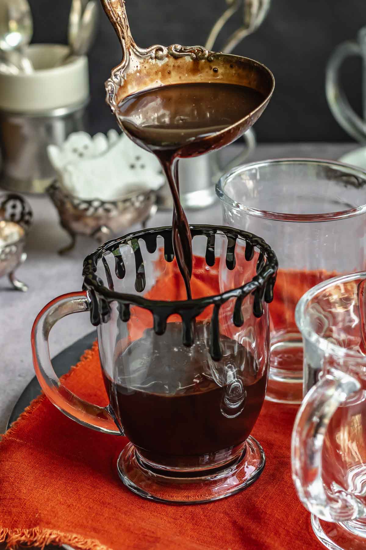 A ladle adds Halloween hot chocolate into a decorated glass mug.
