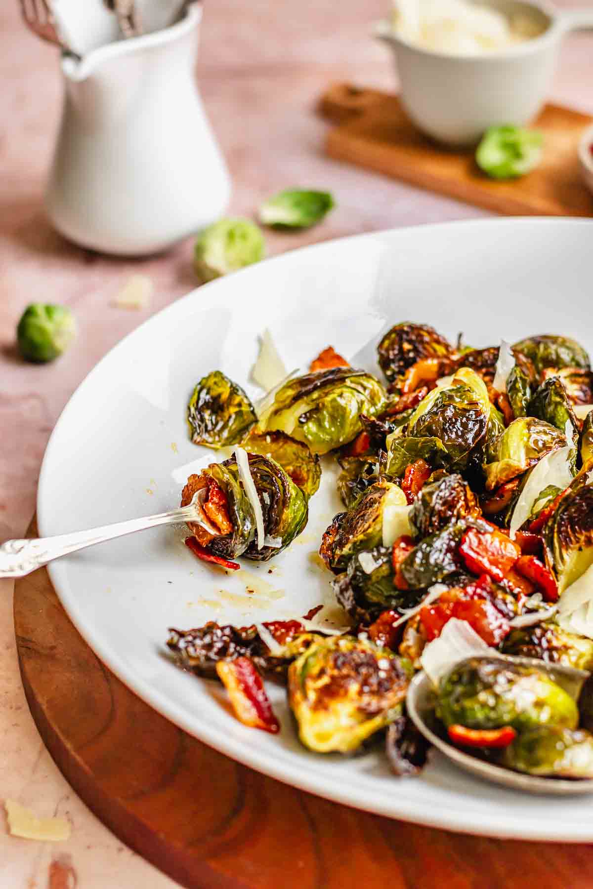 Maple bacon brussels sprouts speared on a fork with others scattered around the platter.