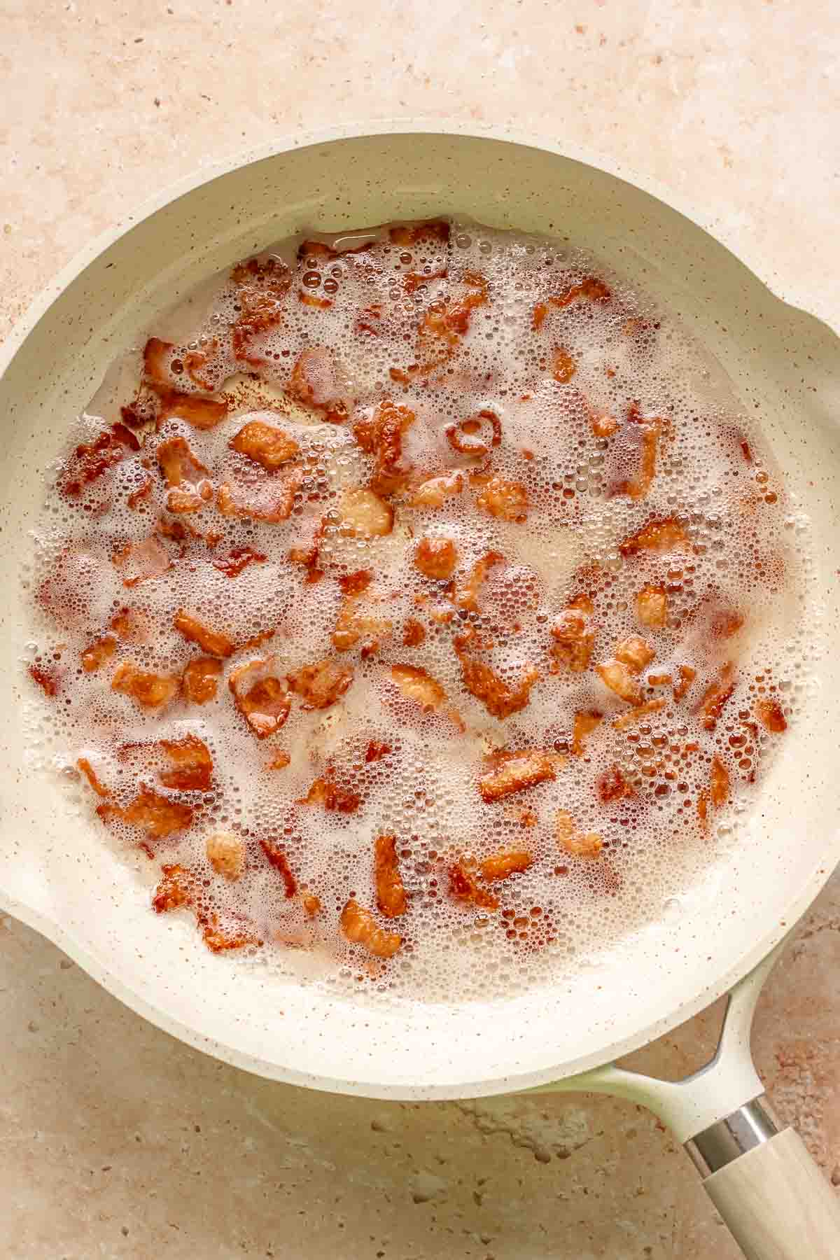 Pieces of bacon frying in a pan.