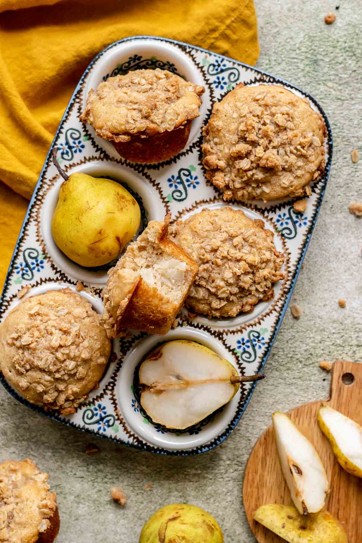 Baked pear muffins in a muffin tin. One sits in the middle with a bite removed.