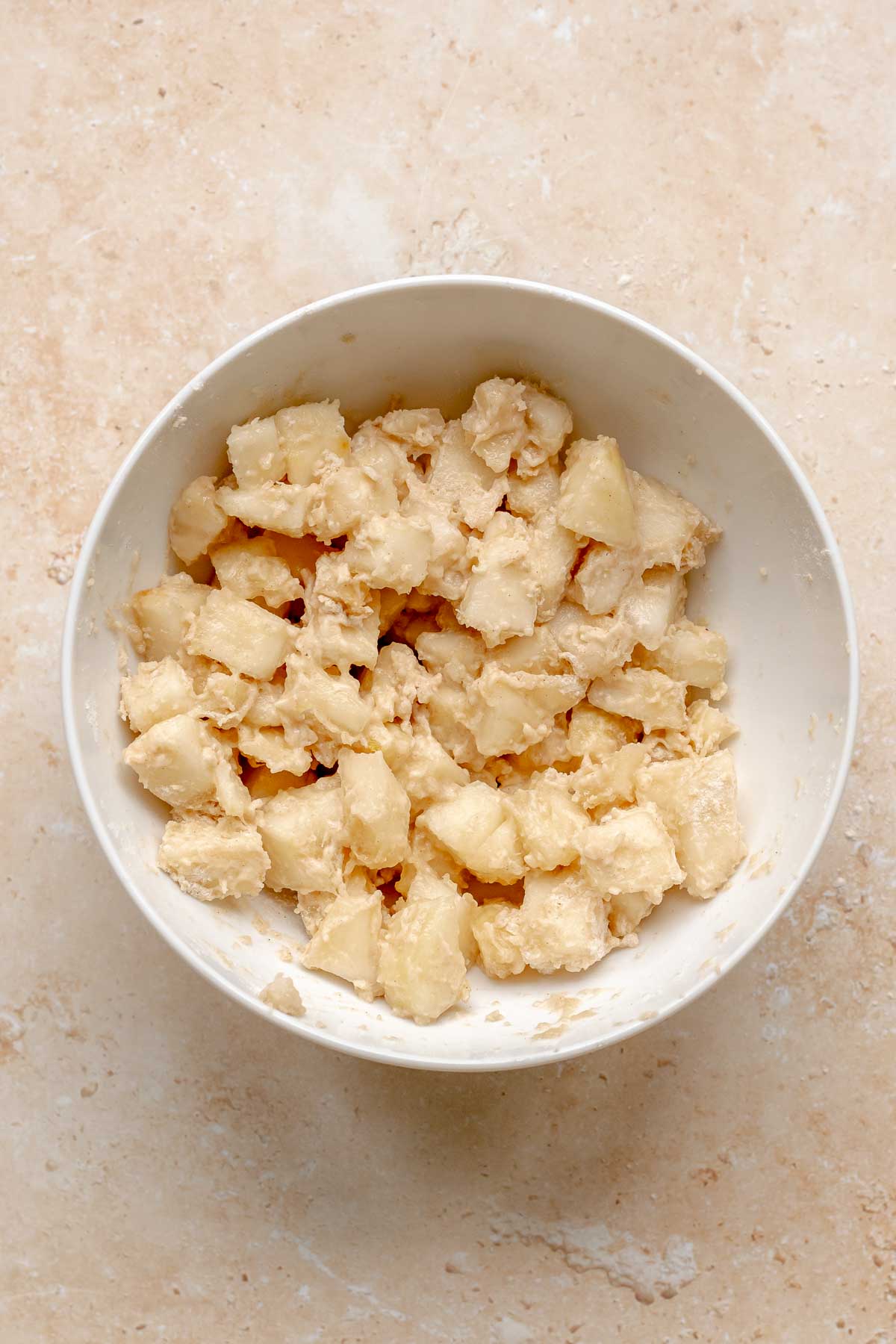Pear chunks tossed with flour in a bowl.
