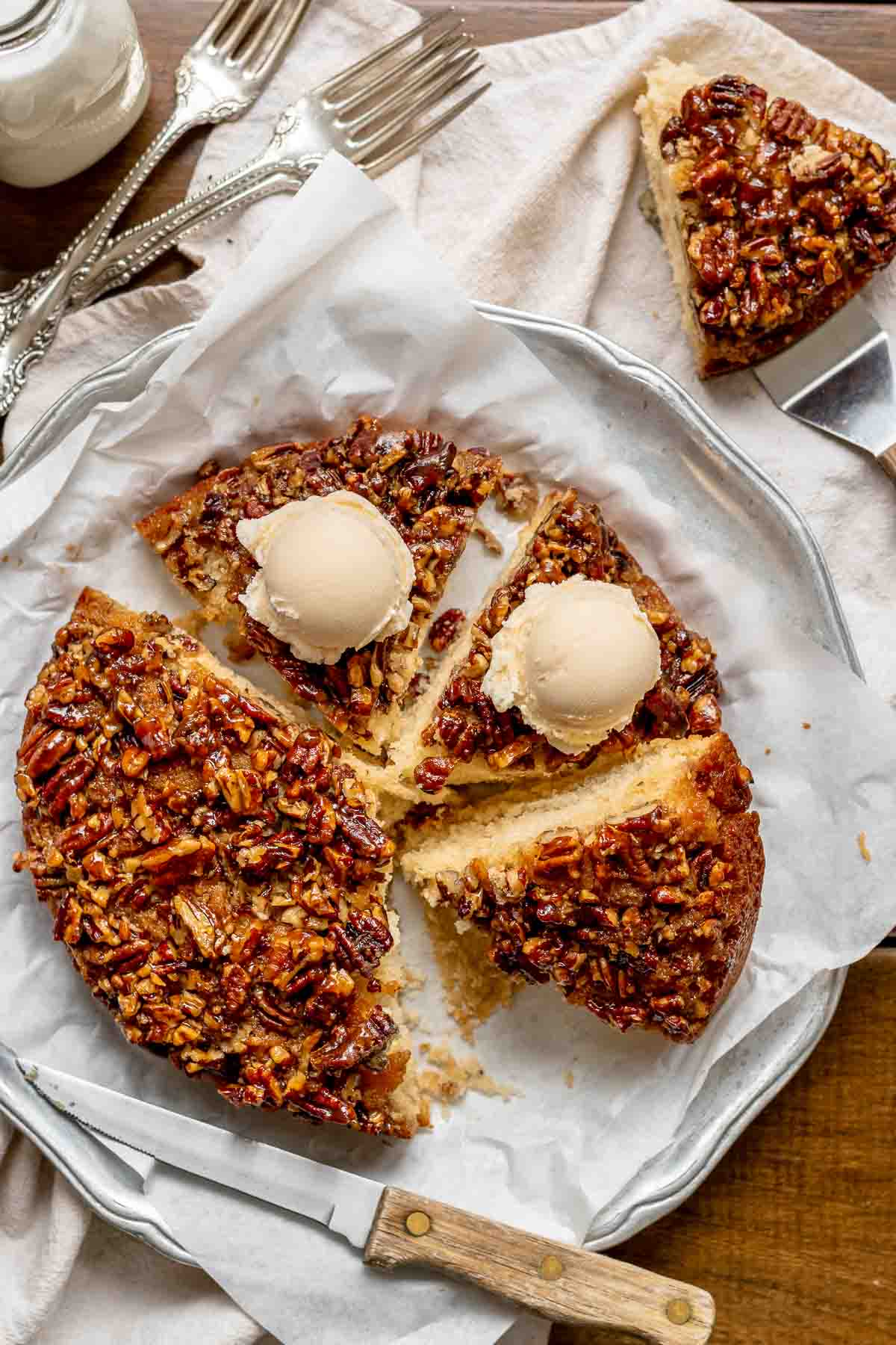 Sliced upside down pecan cake with ice cream scoops on top.