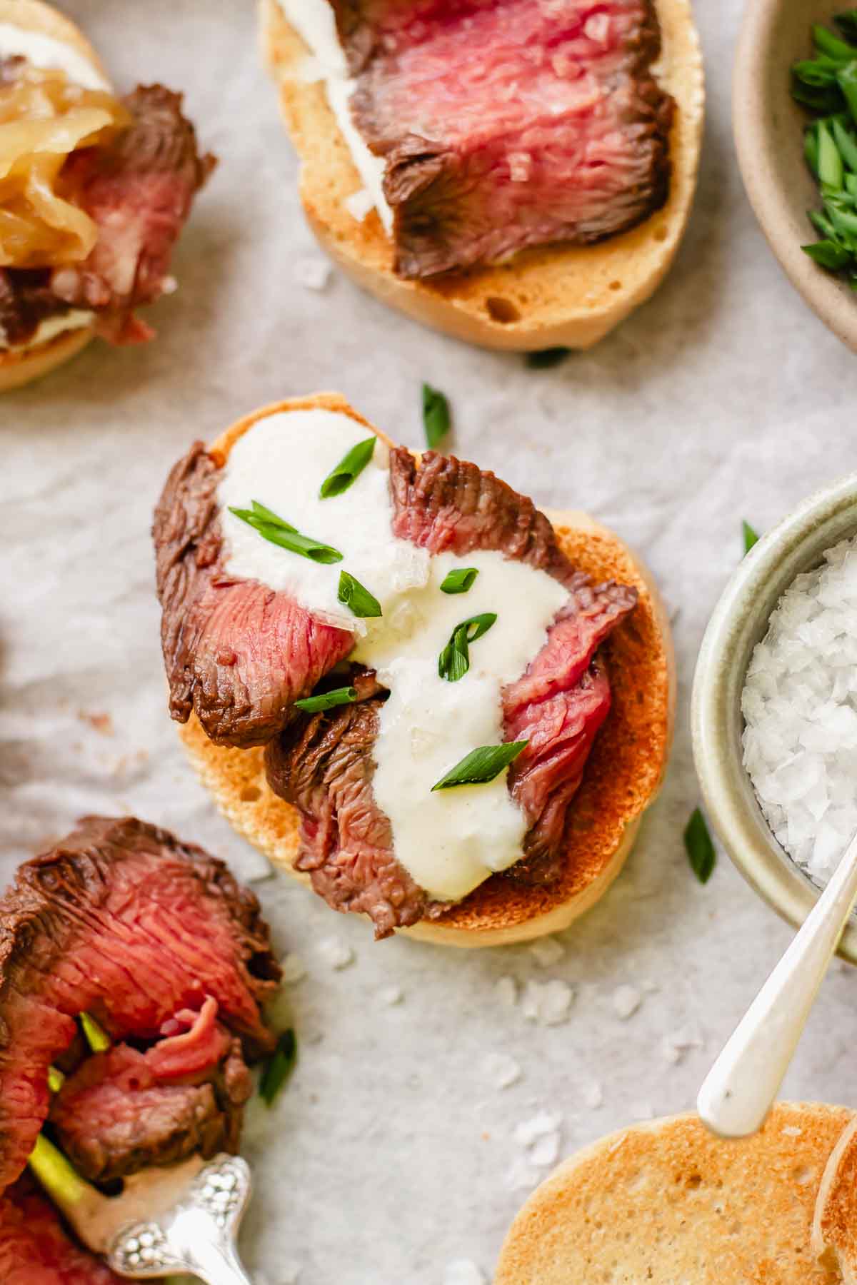Assembled steak and horseradish crostini with chives.