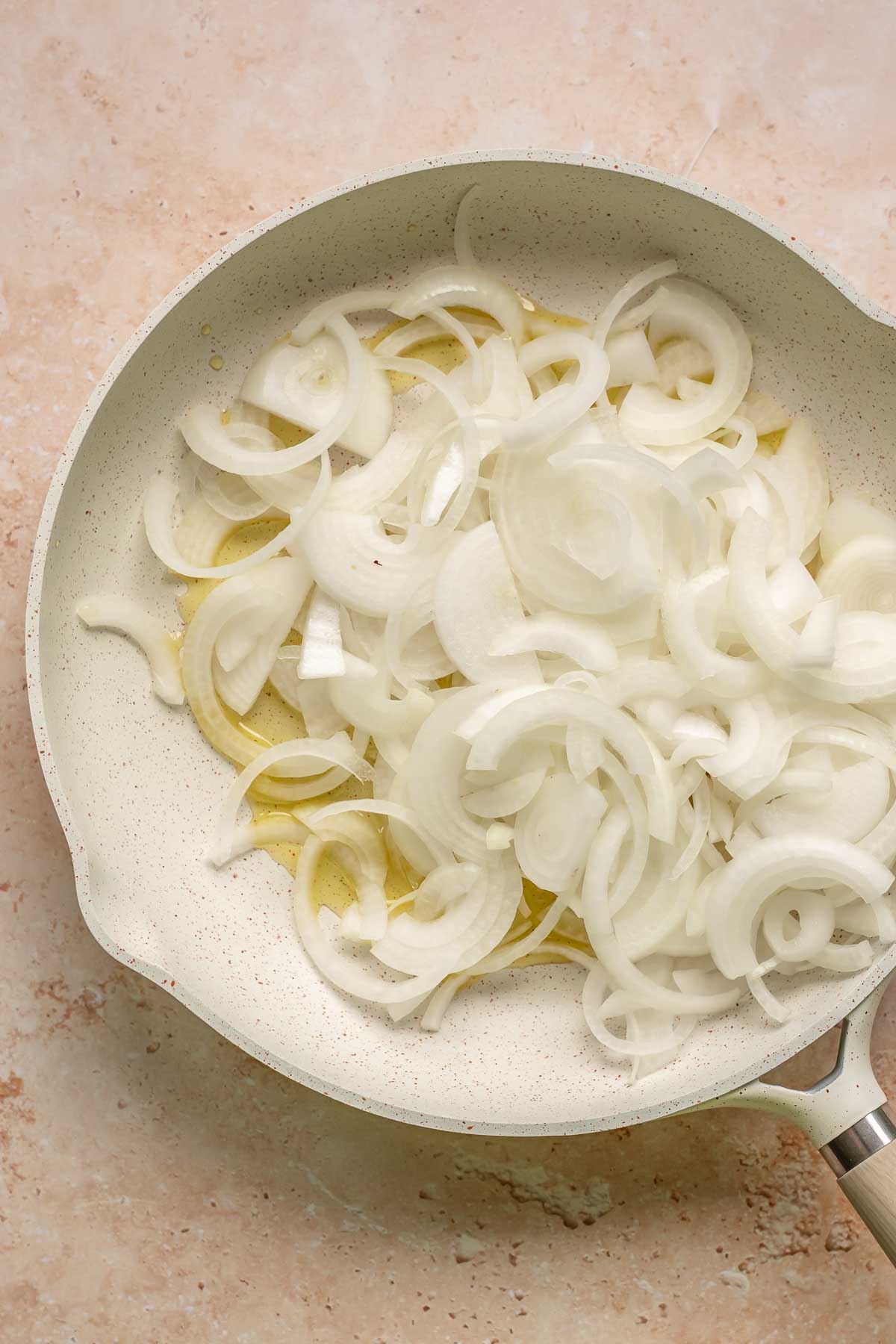 Onions and olive oil in a frying pan.