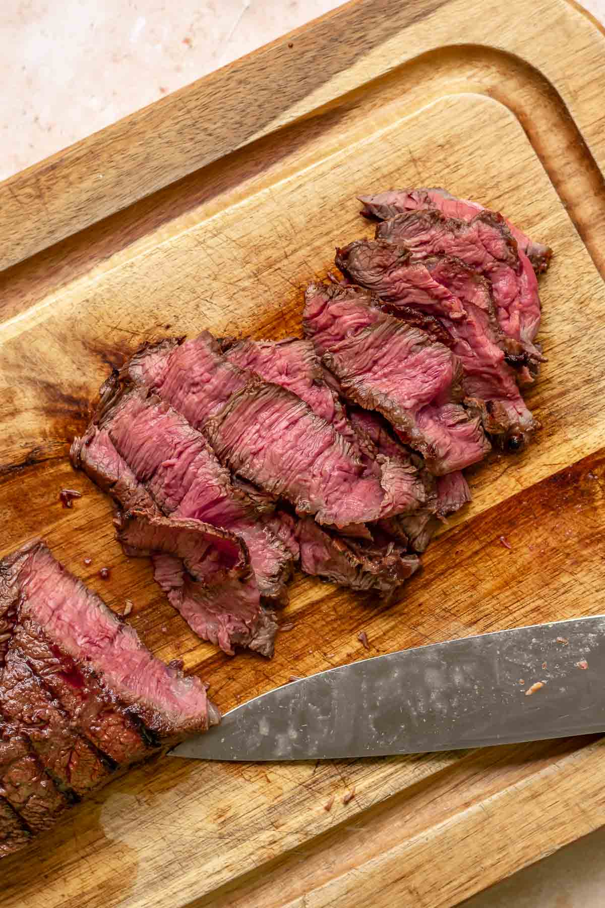 Sliced rare steak on a cutting board.
