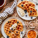 Two plates of sweet potato waffles on a breakfast table.