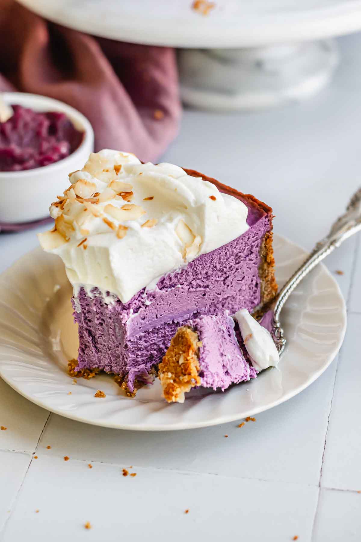 A fork with a piece of ube cheesecake on a plate.