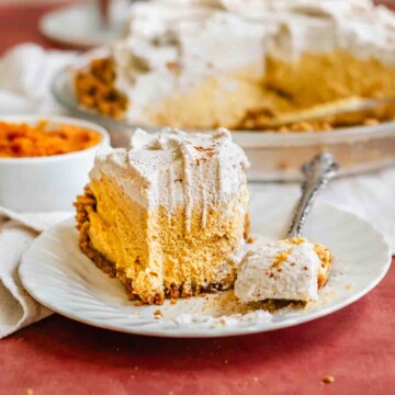 A slice of pumpkin mousse pie on a plate. A fork holds a bite.