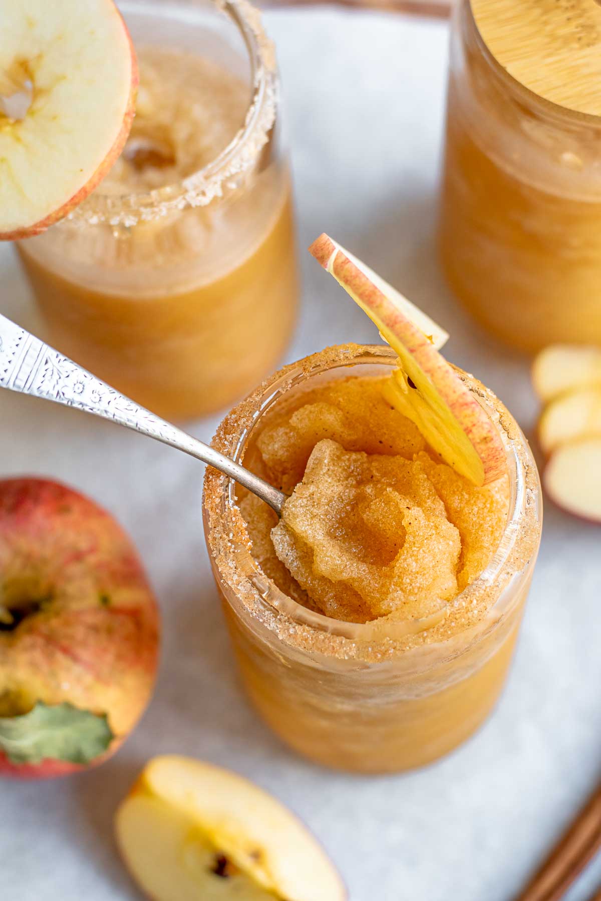 A spoon sits inside an apple cider slushie in a glass.