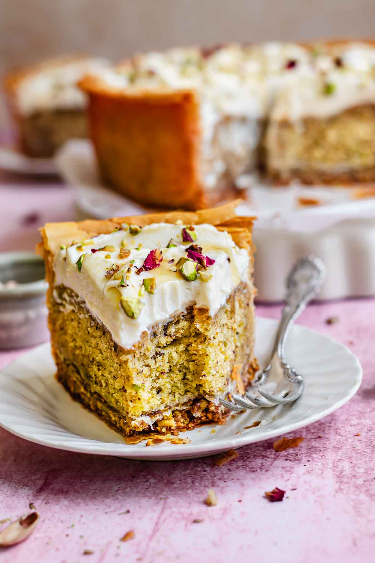 Pistachio cake with a bite removed on a plate.