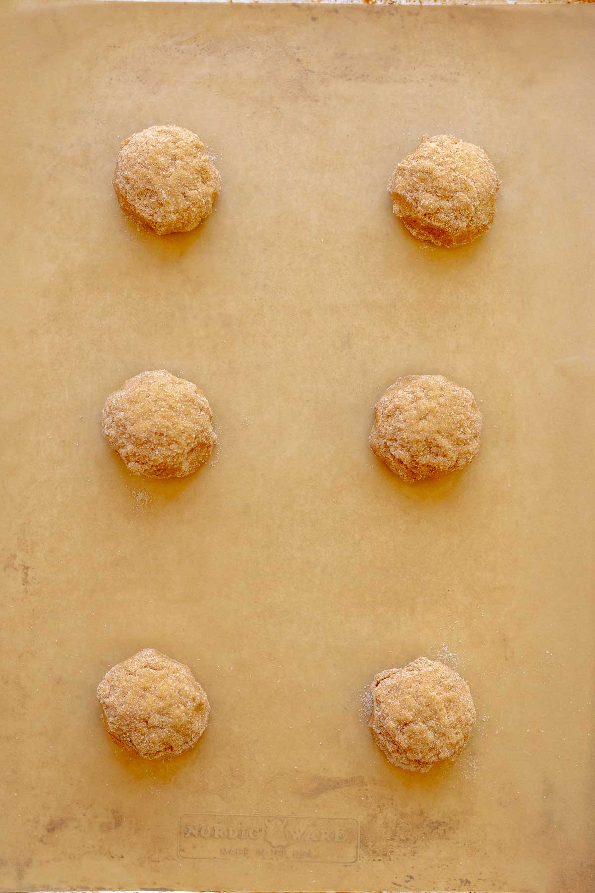 Pumpkin cookies arranged on a baking sheet lined with parchment paper.
