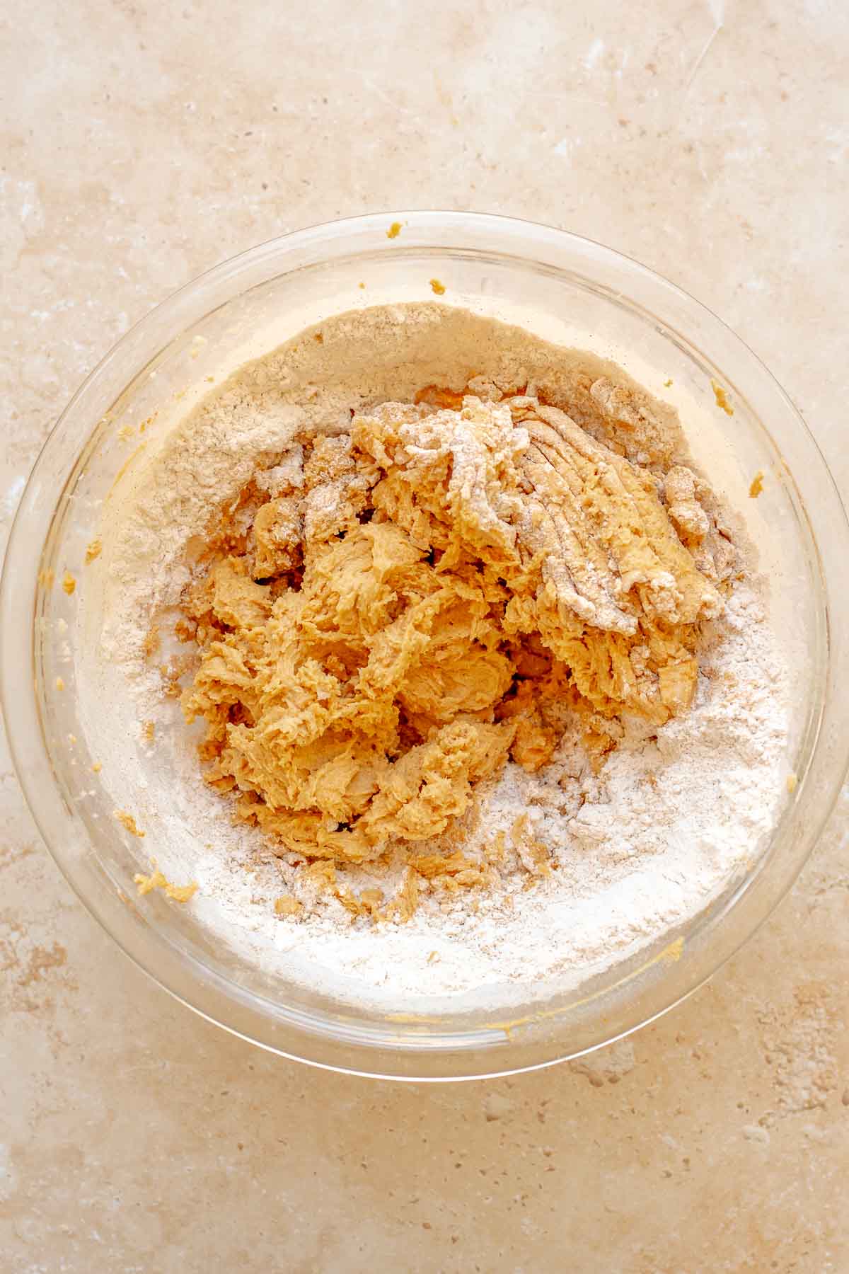 Flour in pumpkin cookie batter in a bowl.