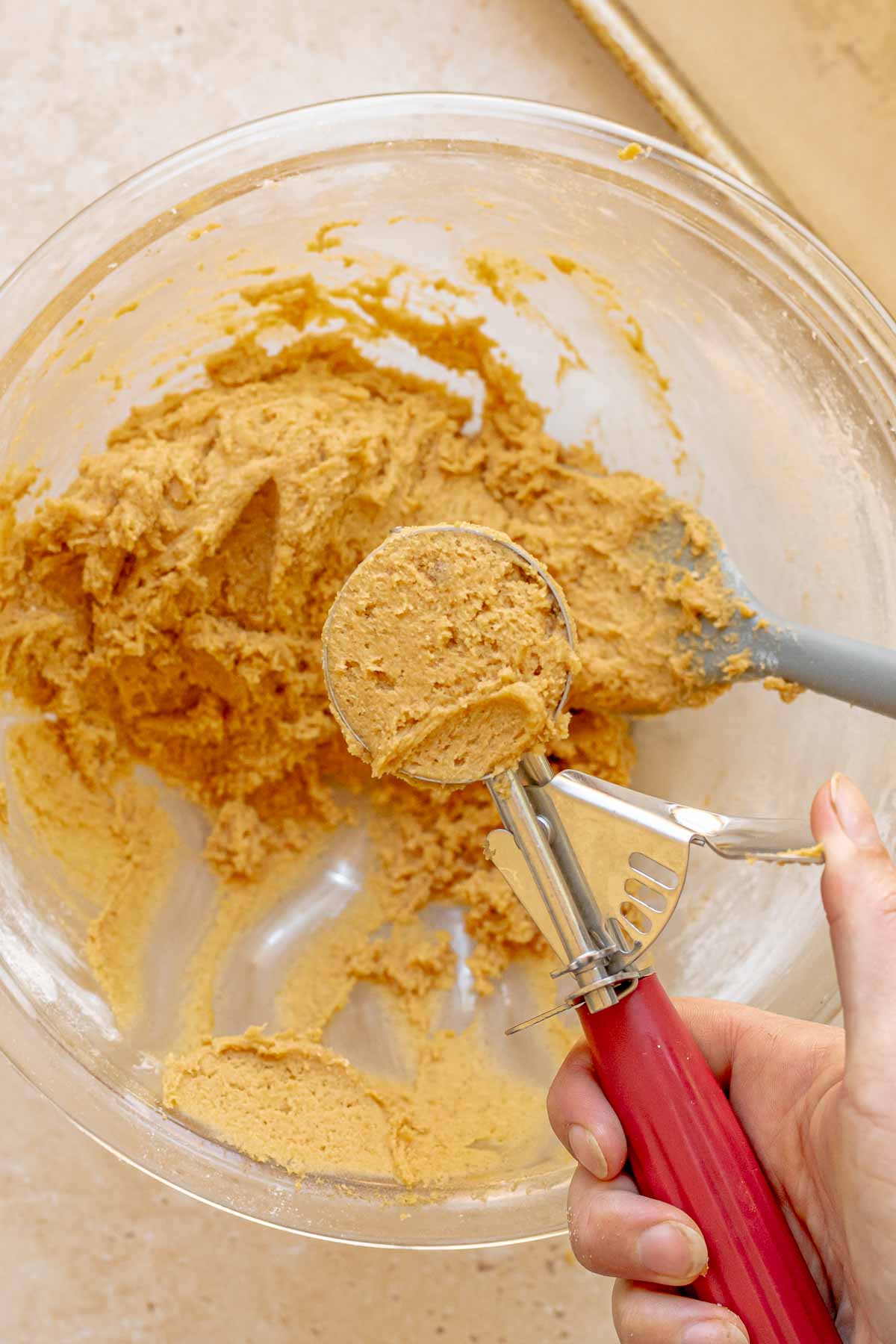 A cookie scoops holds a flush scoop of pumpkin cookie dough.