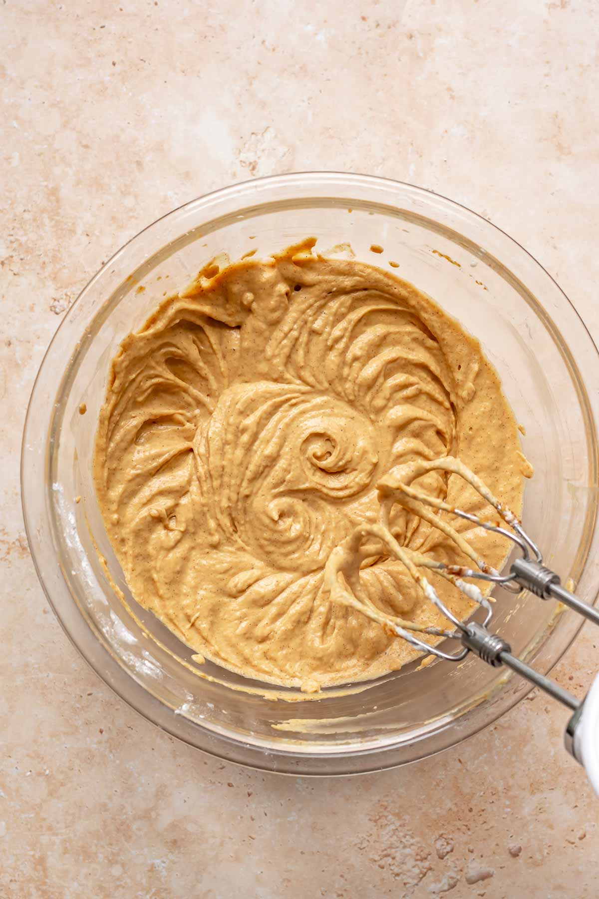 Pumpkin cream cheese batter with beaters mixing in a bowl.