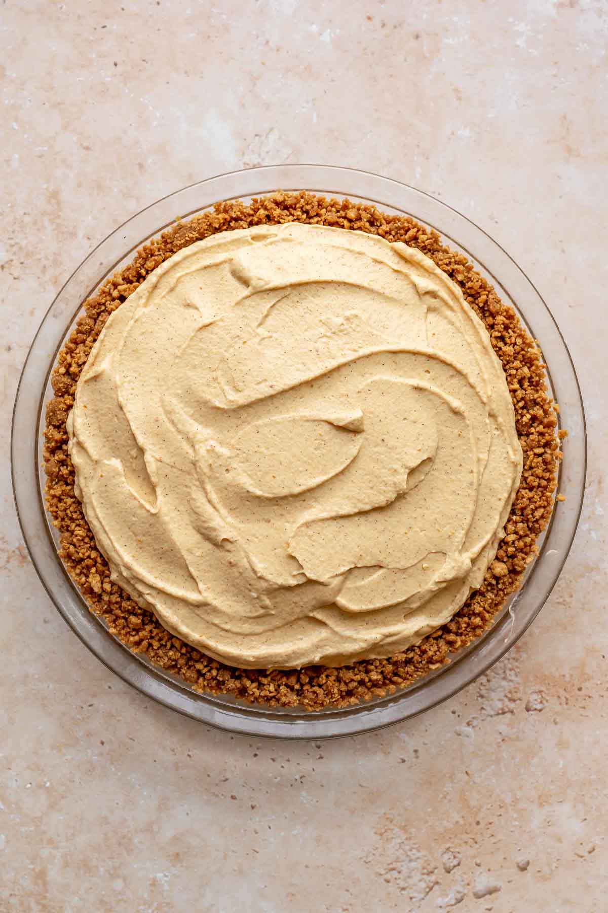 Pumpkin mousse filling spread into a crumb crust in a pie dish.