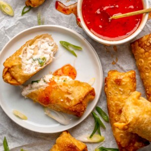 Crab rangoon egg rolls on a platter with dipping sauce.