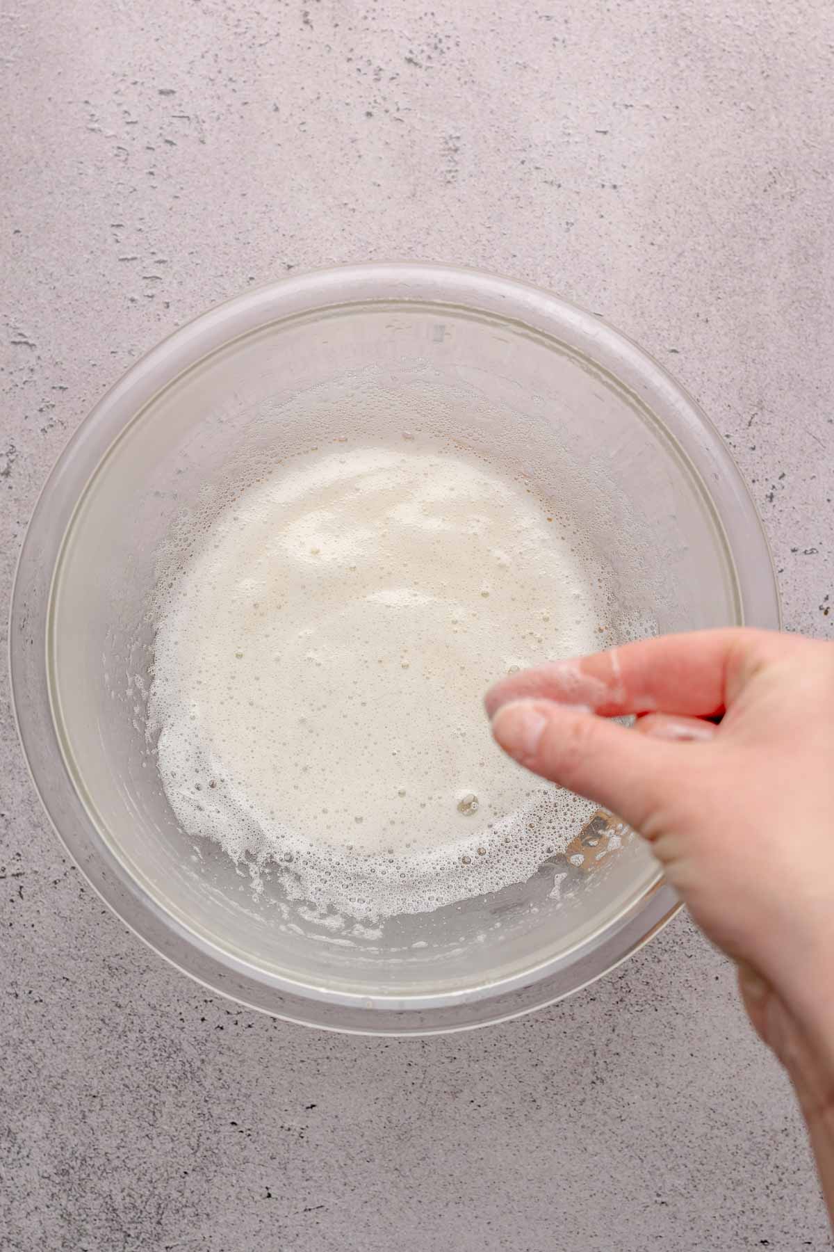 A hand rubs fingers together in egg whites.