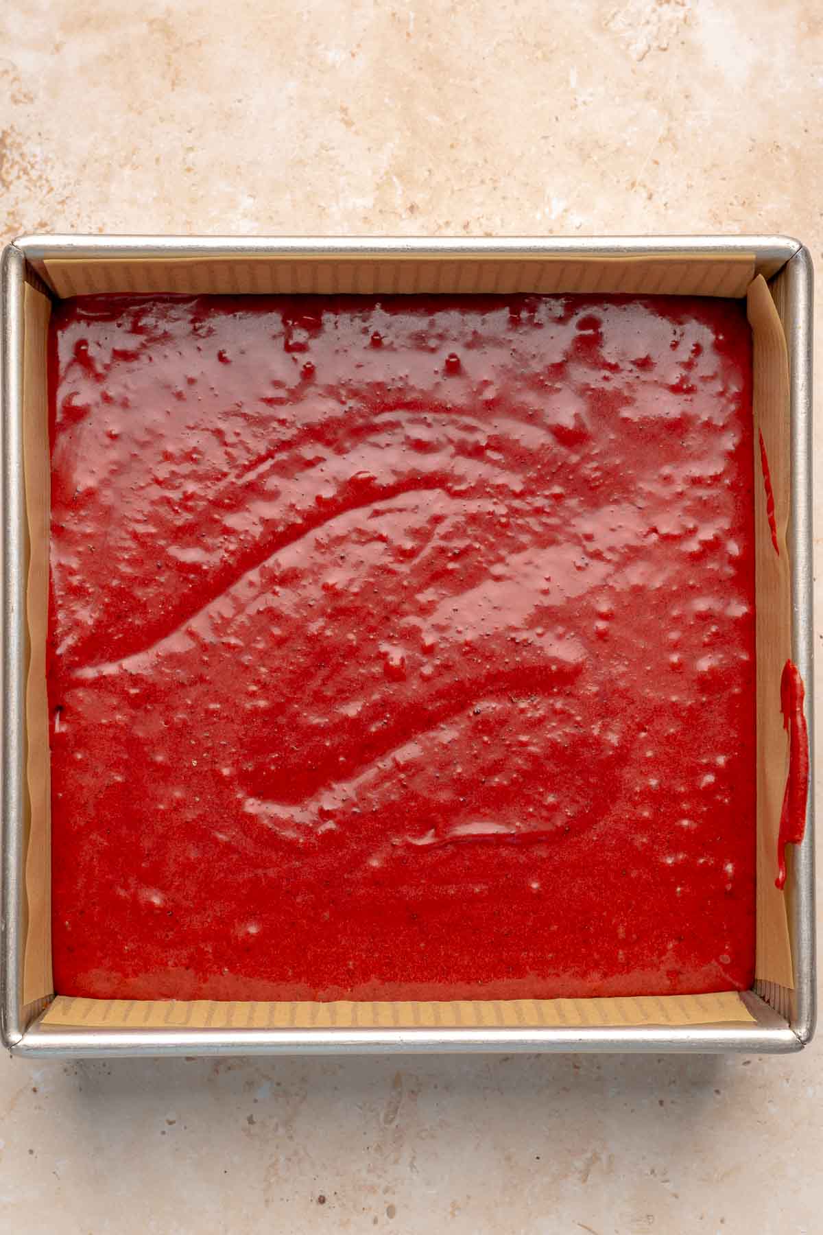 Red velvet brownie batter in a prepared square pan.