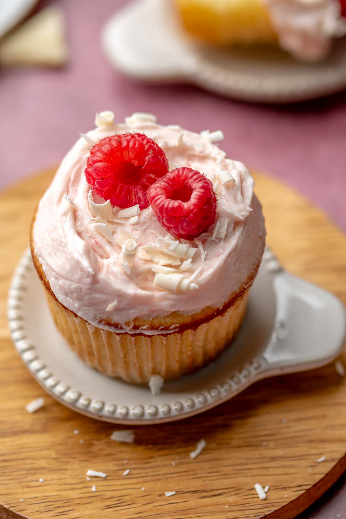 Raspberry white chocolate cupcake on a small plate.